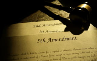 Judge's gavel resting on a printed copy of the 5th Amendment text