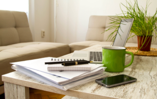 Home office workspace for a home-based business in Clark County, Nevada, featuring a laptop, business documents, notebook, coffee mug, and smartphone.
